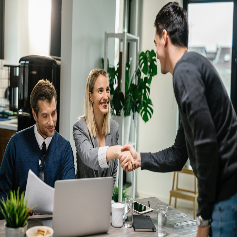 Real estate agents handshaking with a client during the meeting at home.