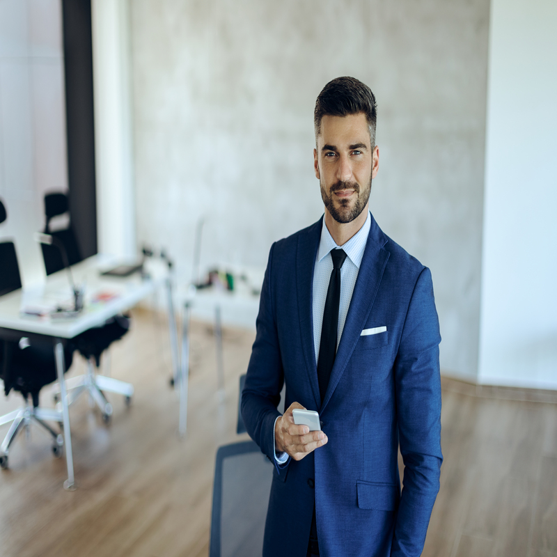 Young businessman using mobile phone in the office and looking a
